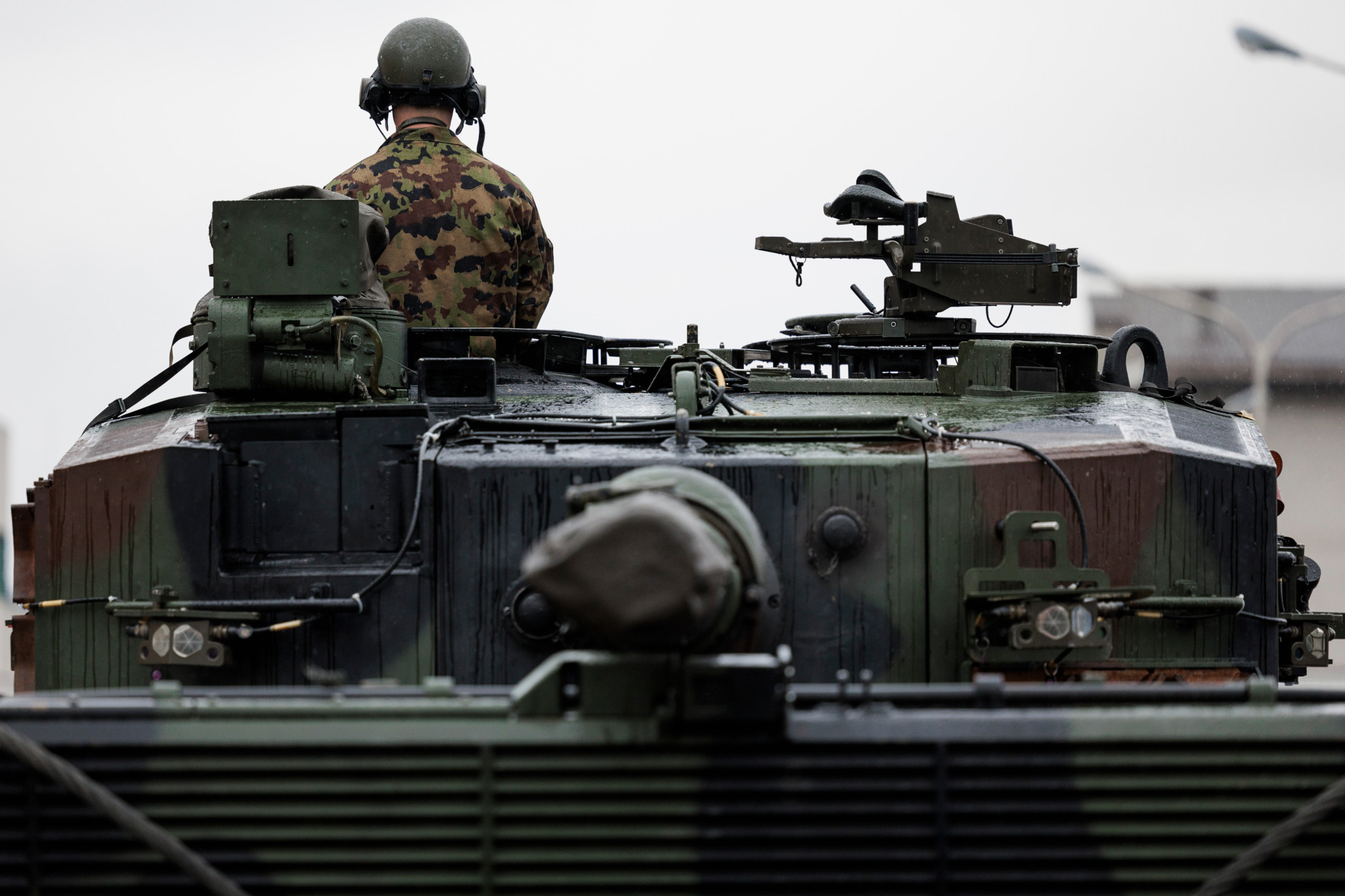 Leopard 2 Kampfpanzer werden von einem Soldaten in Tarnuniform auf einem Transportzug in Thun überwacht, Vorbereitung für Ausland-WK TRIAS25, 15. April 2025.